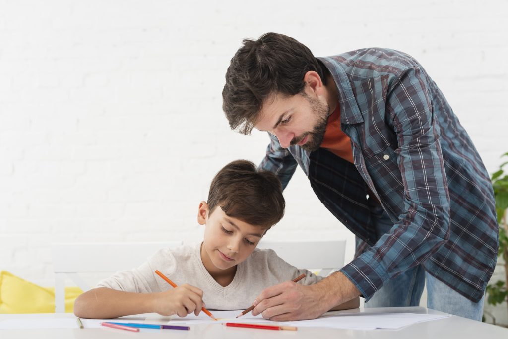 father looking his son doing homework